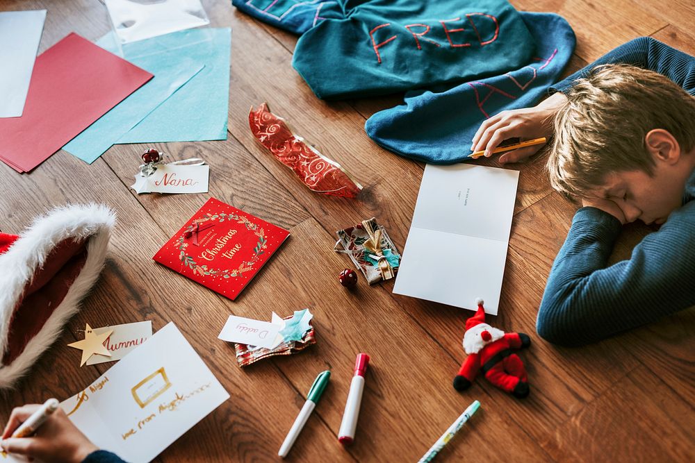 Kids writing Christmas cards on wooden floor