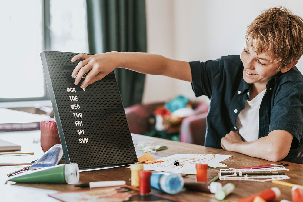 Boy creating text on black letter board