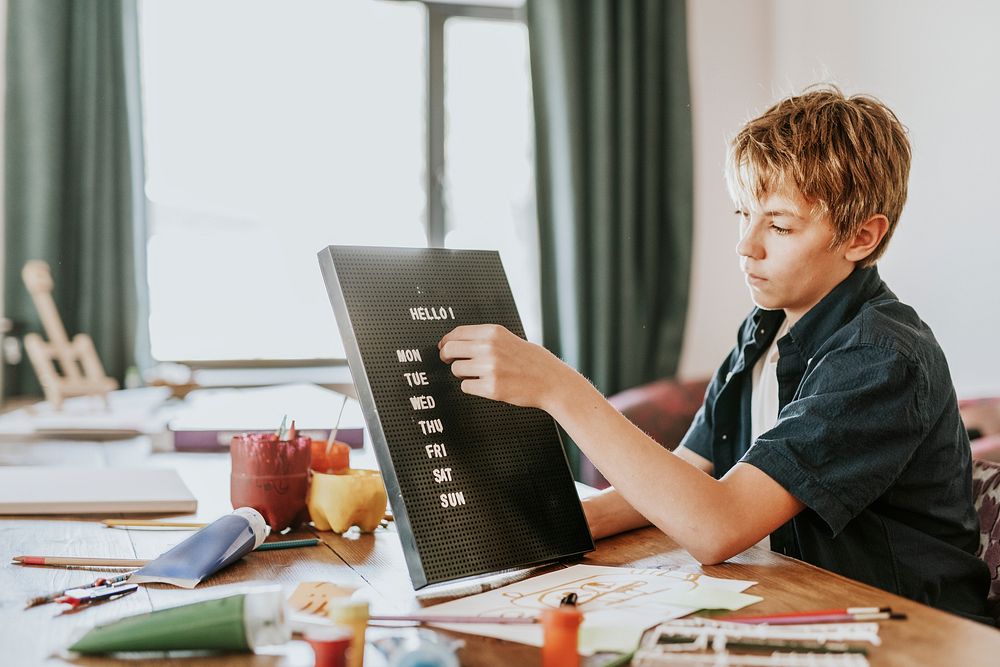 Boy creating text on black letter board