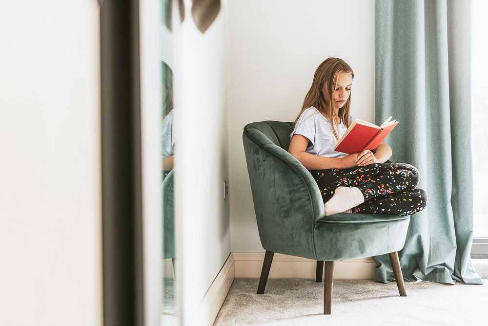 Young girl reading a book on a couch, new normal hobby