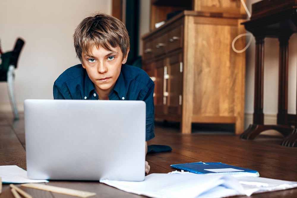 Boy using laptop on wooden floor, the new normal