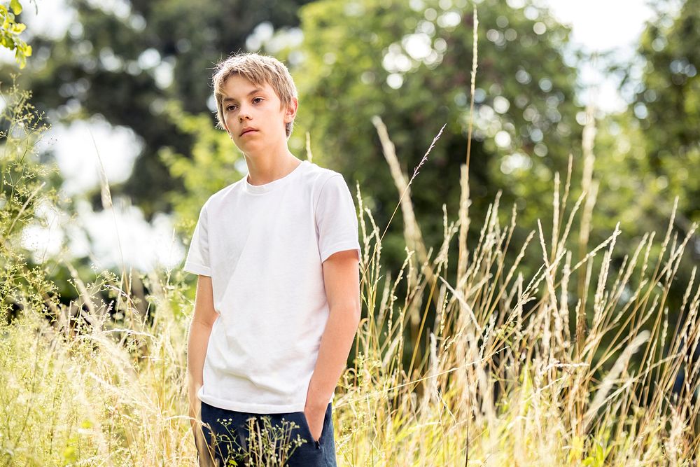 Boy in white tee, summer day in a grass field