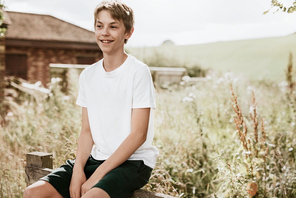 Boy sitting on wooden fence, summer vacation