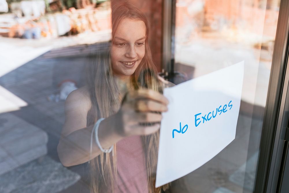 No excuses paper, young girl showing sign through glass window, the new normal