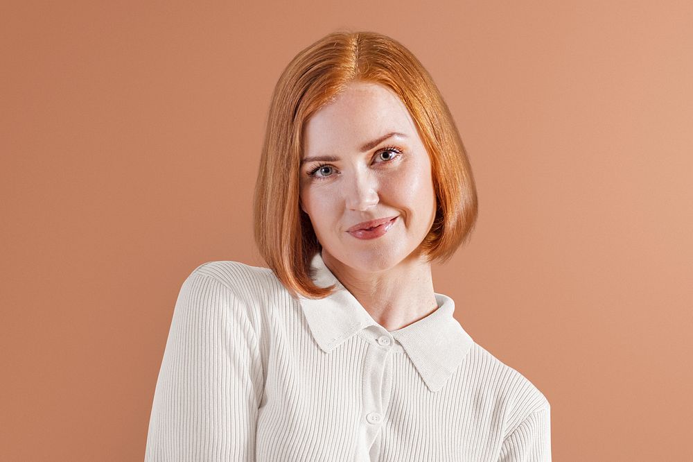 Cheerful ginger-haired woman in beige knitted shirt