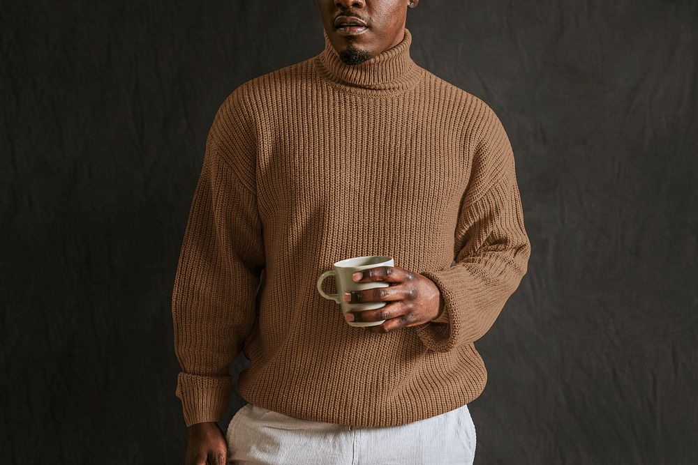 Man wearing brown turtleneck sweater, holding coffee cup
