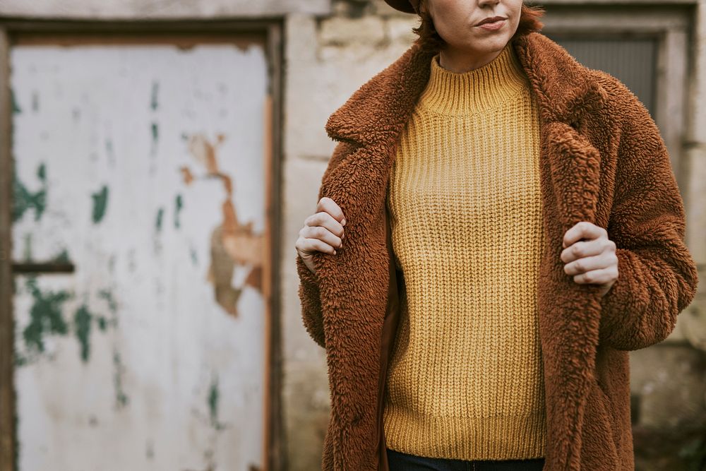 Woman wearing brown coat over mustard yellow sweater