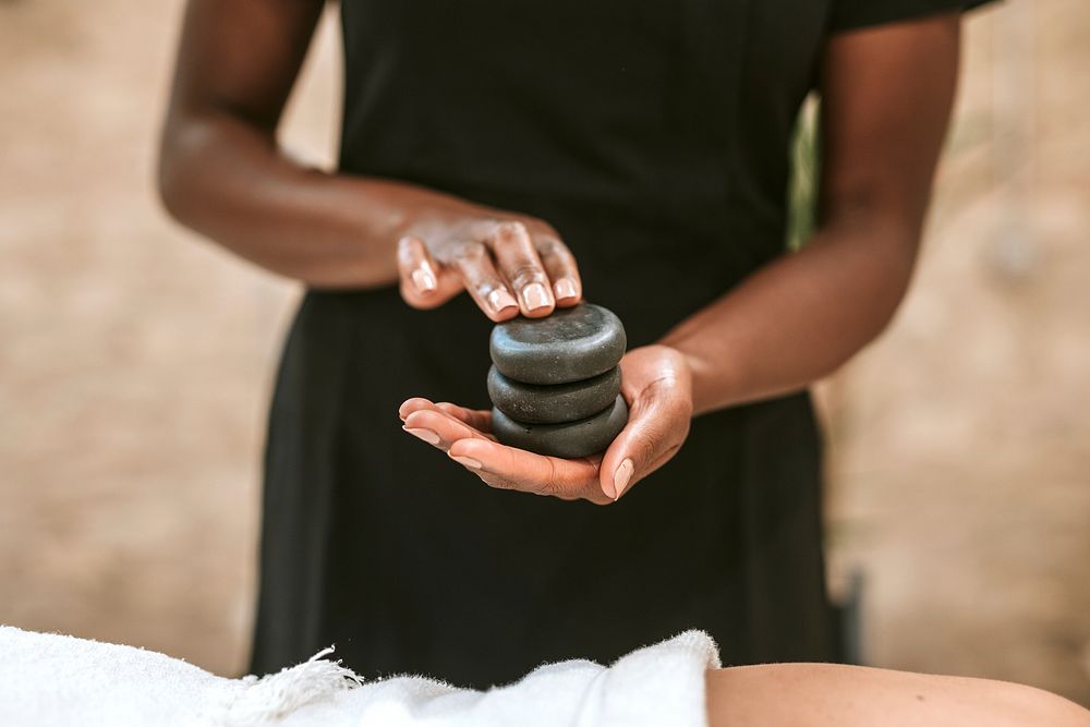 African American woman holding spa stones for massage