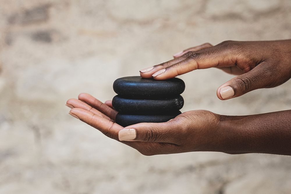 African American woman holding spa stones for massage
