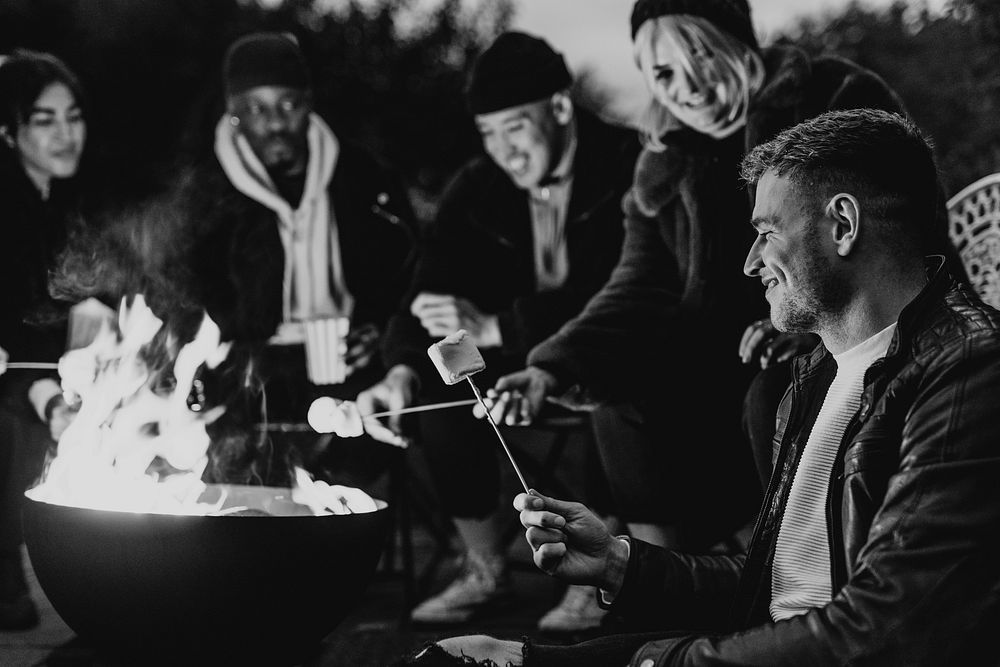 Friends enjoying s'mores and marshmellow together by the bonfire 