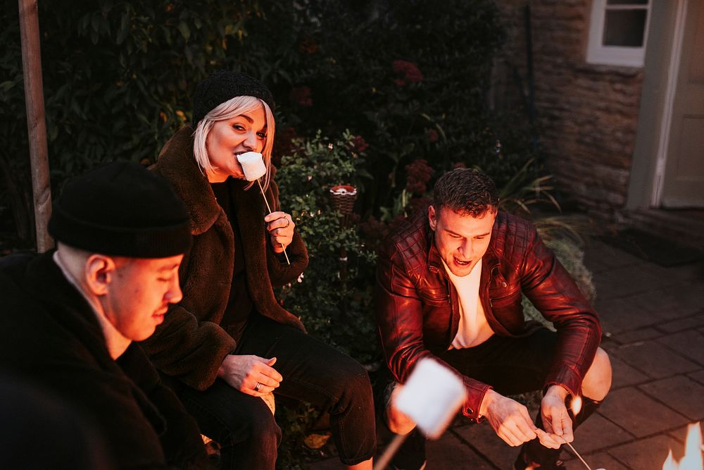 Friends enjoying s'mores and marshmellow together by the bonfire 