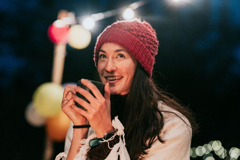 Woman keeping warm with hot chocolate, a beanie, and a shawl 