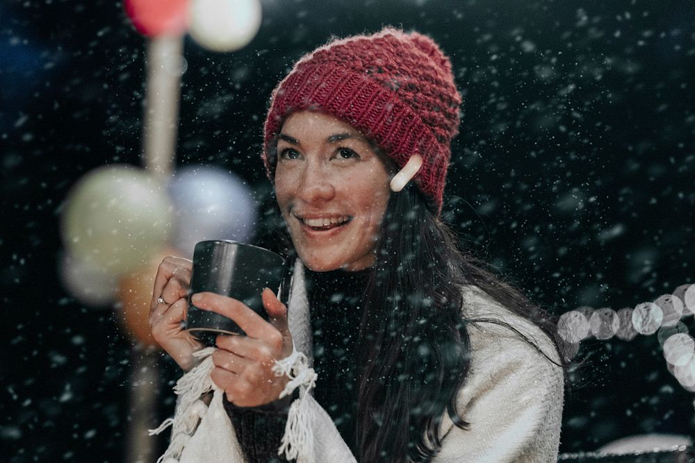 Woman keeping warm with hot chocolate, a beanie, and a shawl 