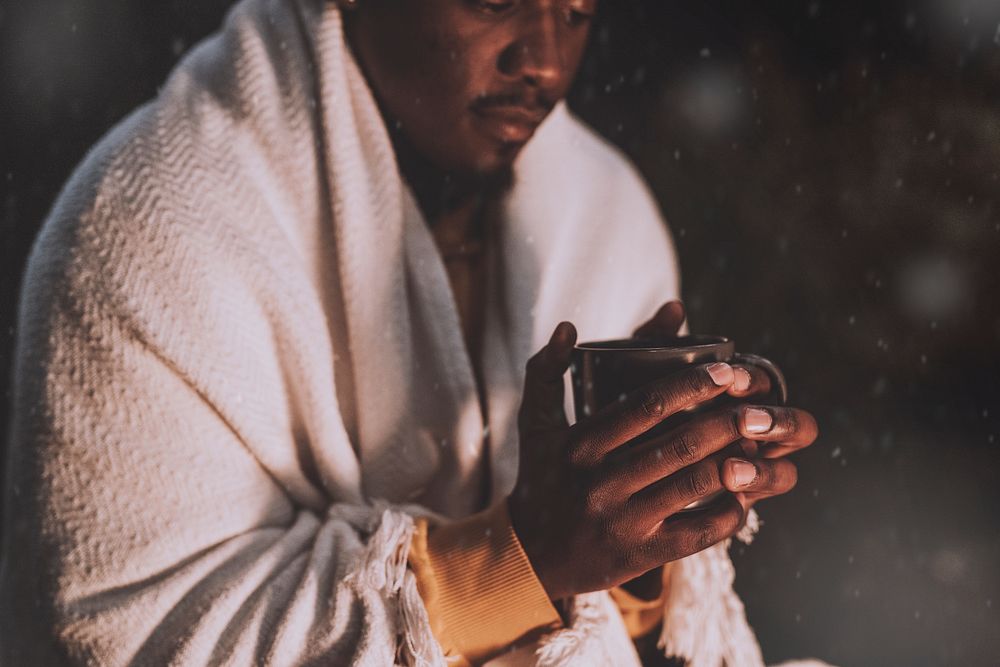 Man keeping warm with hot chocolate and a shawl