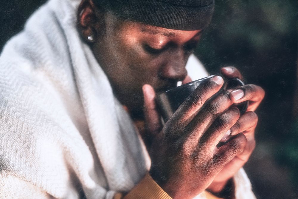 Man keeping warm with hot chocolate, a beanie, and a shawl