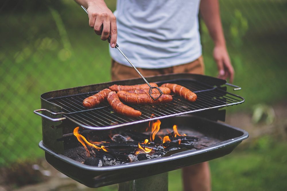 Man cooking sausages on a barbecue grill. Visit Kaboompics for more free images.