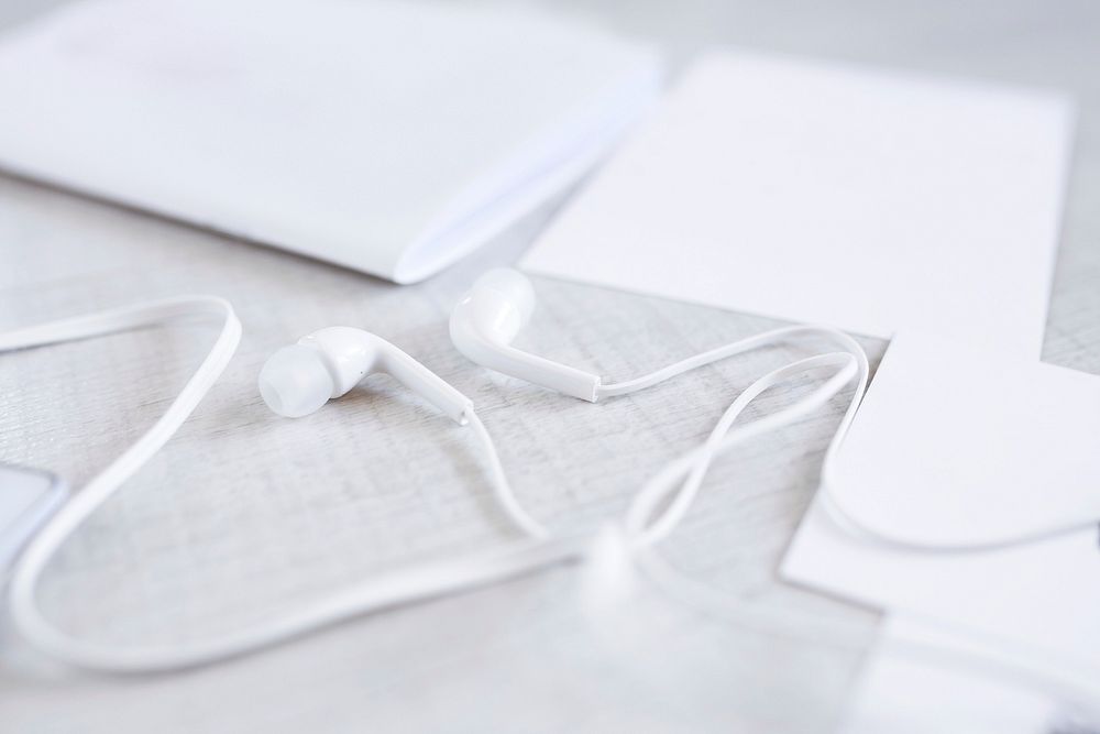 Close up of white earphones on a table. Visit Kaboompics for more free images.