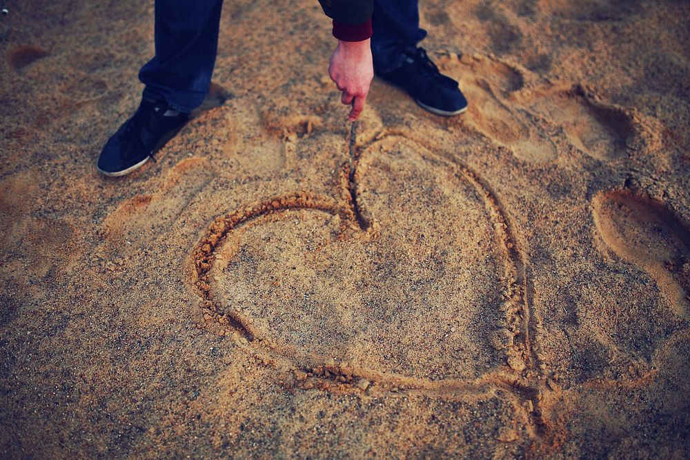 Man drawing a heart in the sand. Visit Kaboompics for more free images.