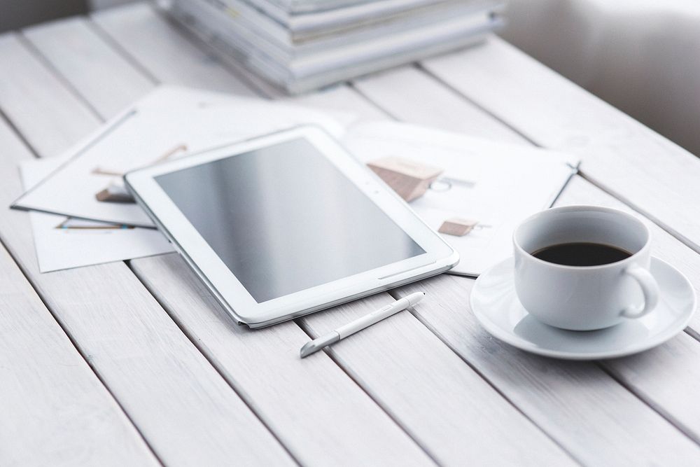 Tablet and a coffee cup on a table. Visit Kaboompics for more free images.
