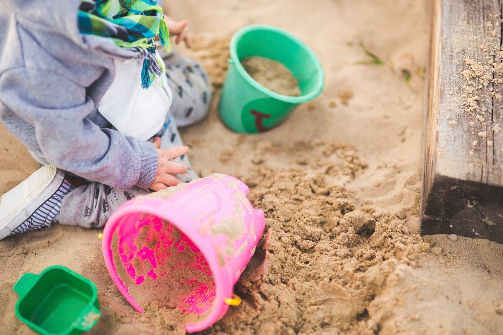 Toddler playing with sand. Visit Kaboompics for more free images.
