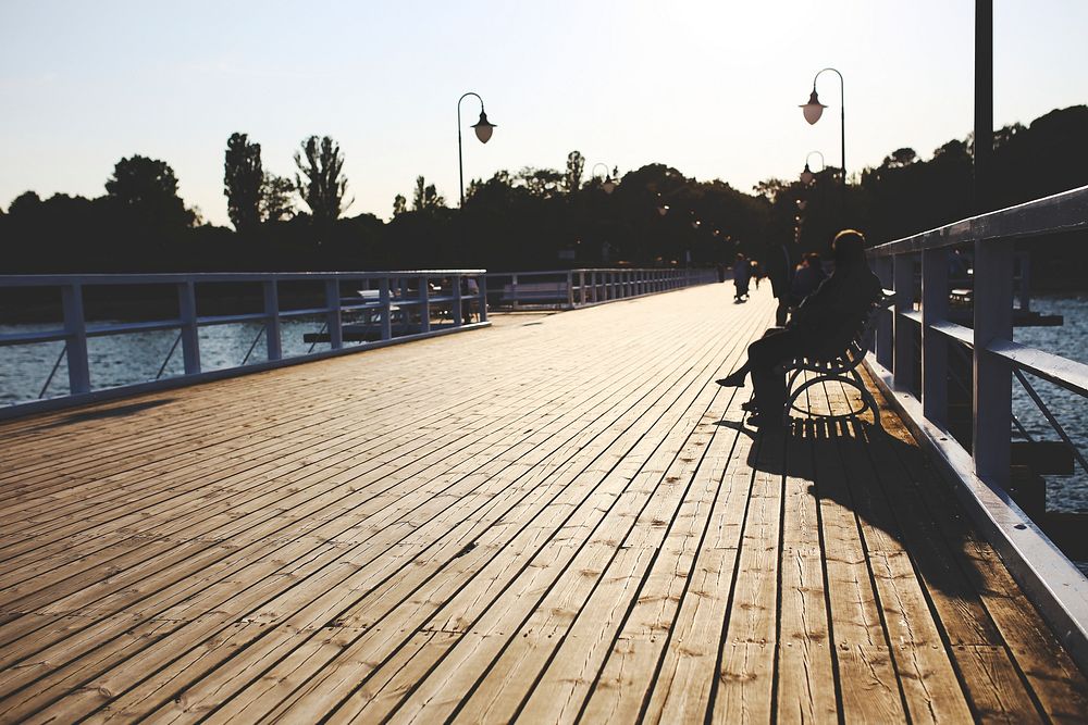 Men sitting at a wooden pier. Visit Kaboompics for more free images.