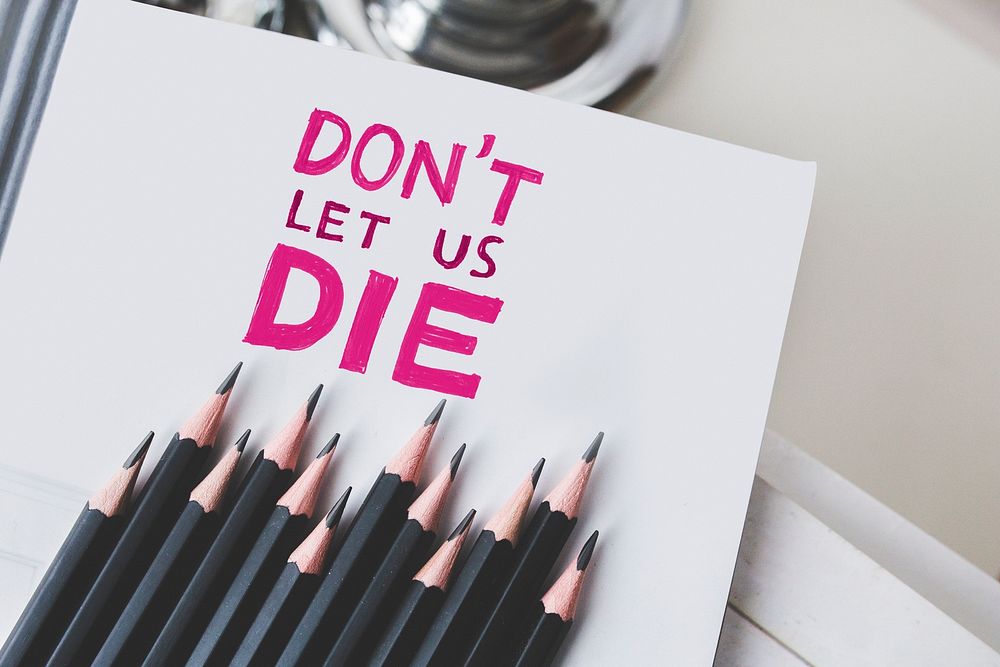 Close up of paper with the phrase "Don't let us die". Visit Kaboompics for more free images.