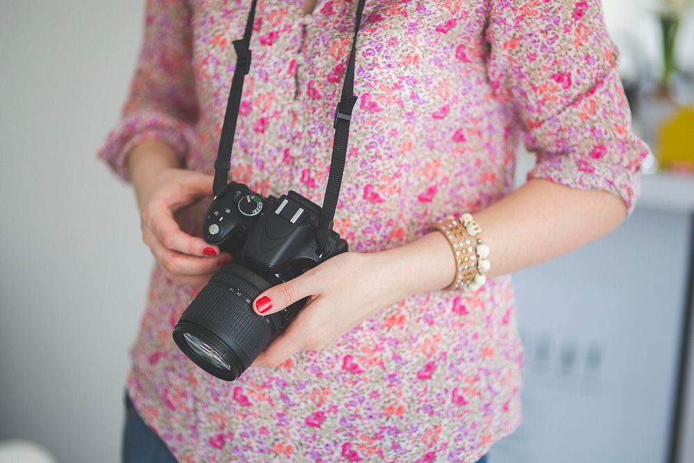 Photographer holding a DSLR camera. Visit Kaboompics for more free images.