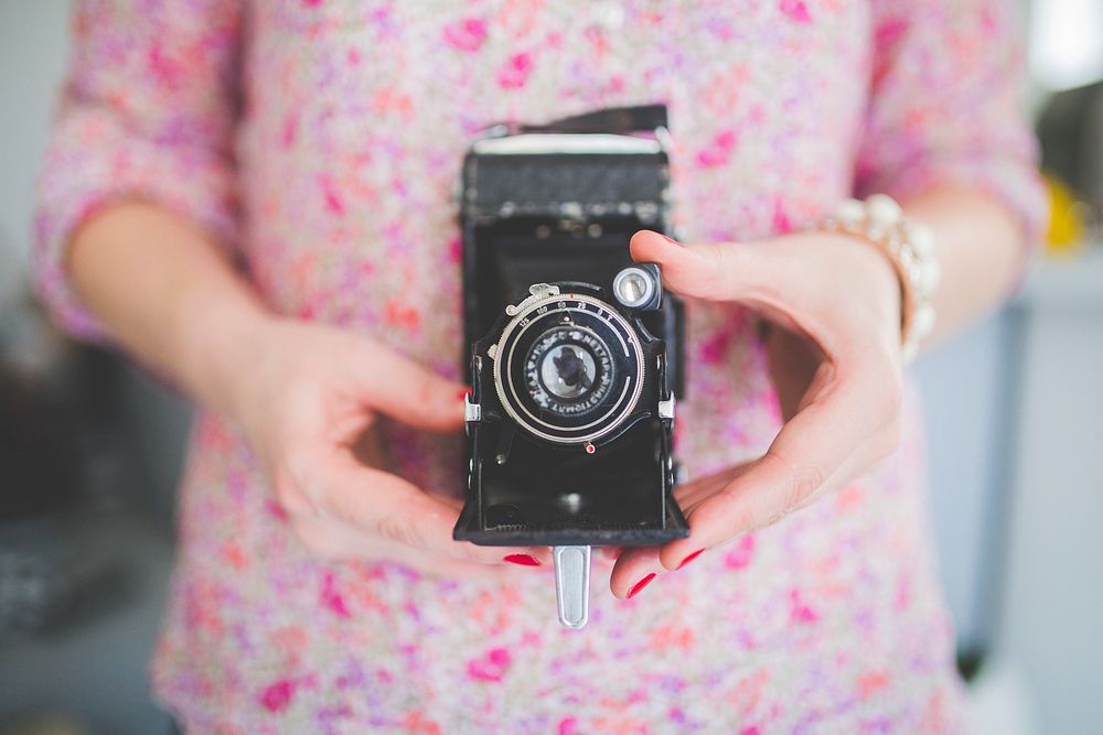 Woman holding vintage analog film camera. Visit Kaboompics for more free images.