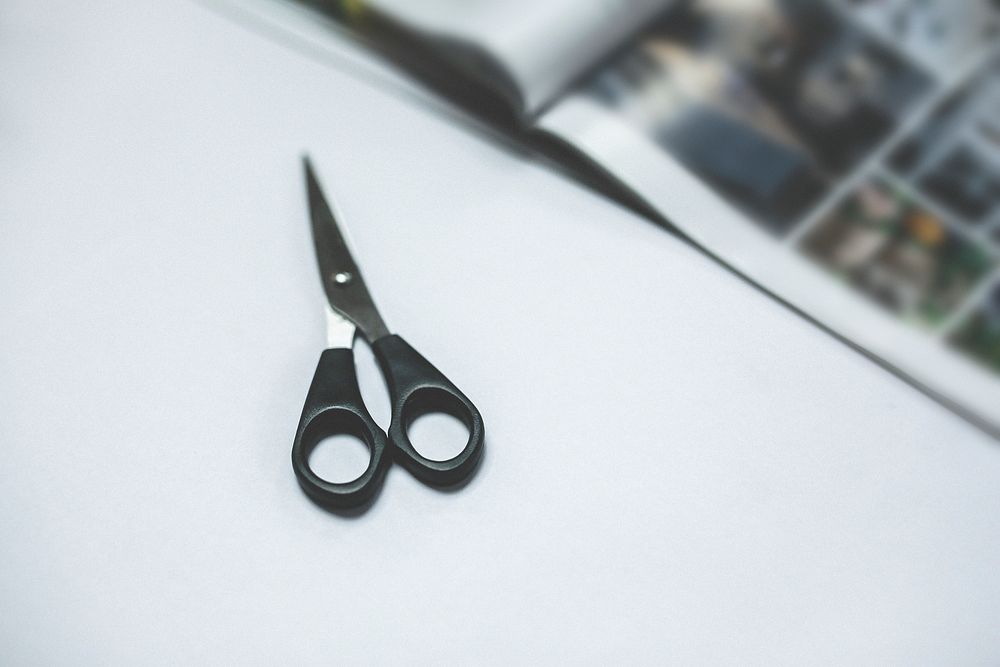Black scissors on white table. Visit Kaboompics for more free images.