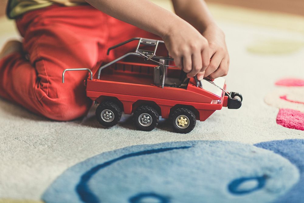 Young kid playing with a toy car on a carpet