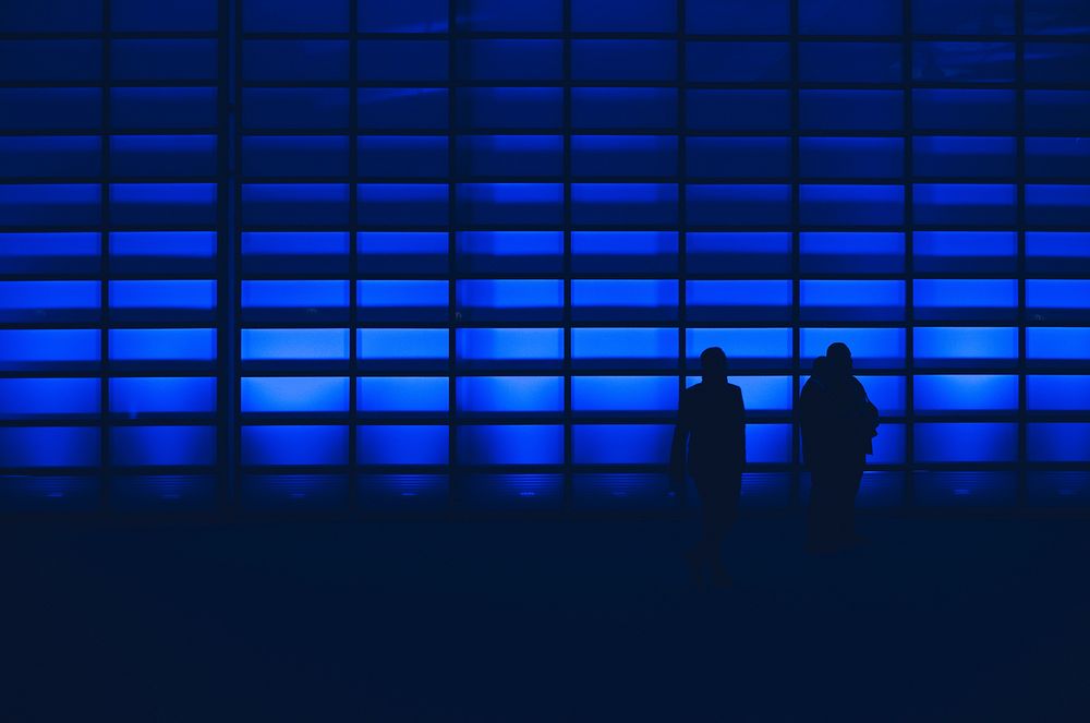 Silhouetted men with blue light wall