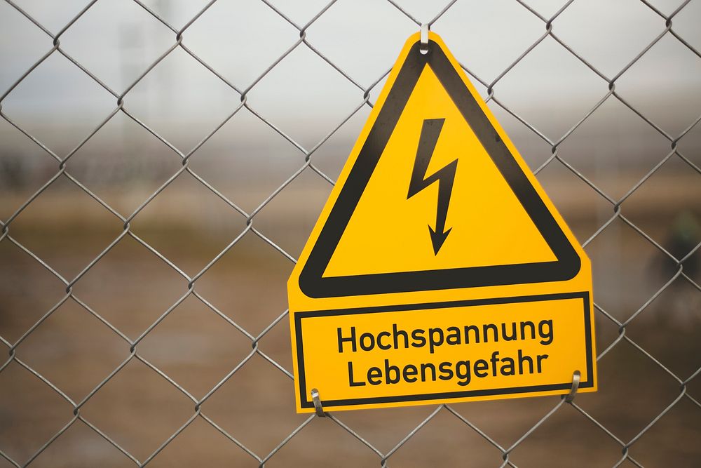 High voltage warning sign hanging on a fence