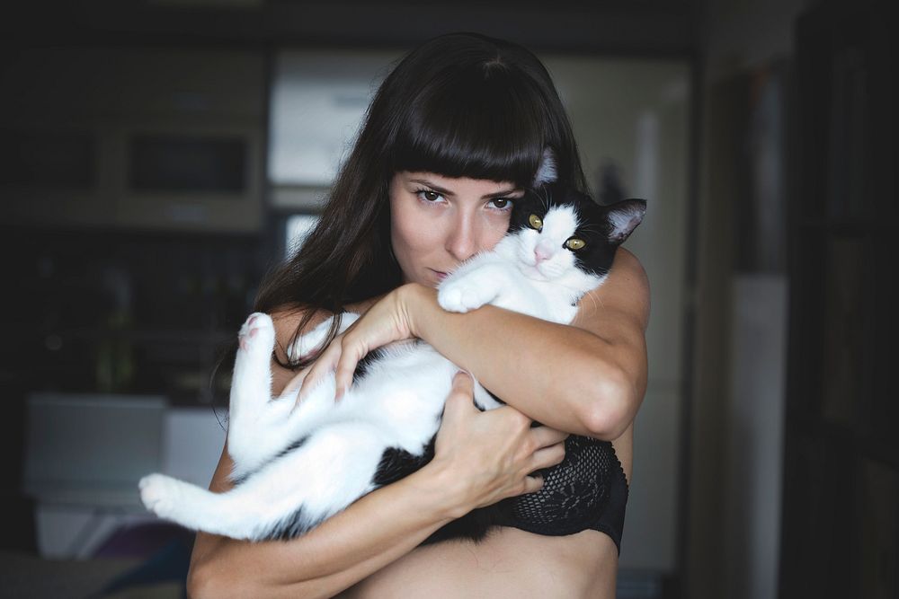 Brunette woman in brassiere holding her cat