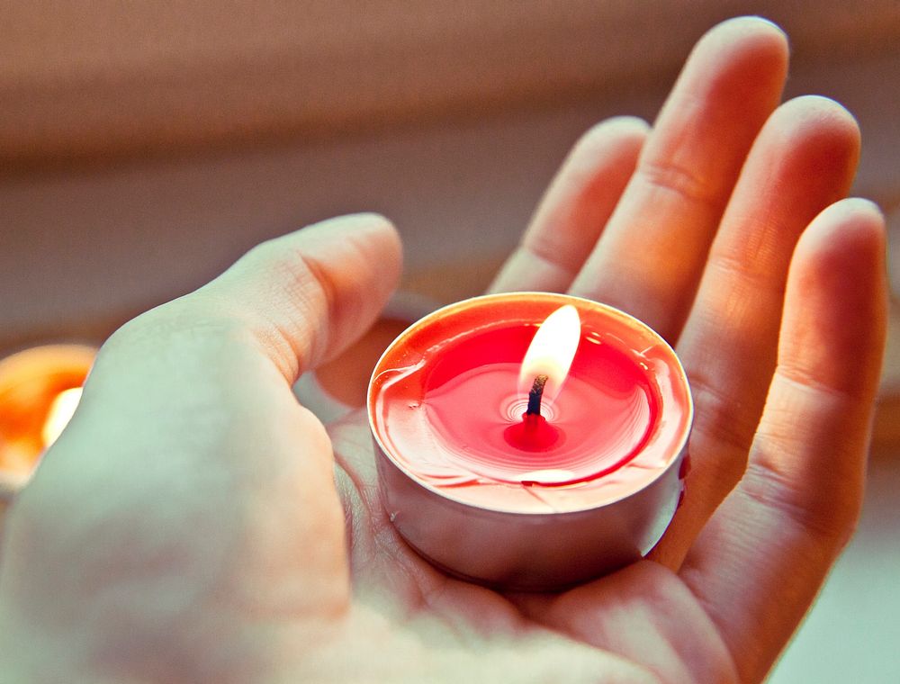 Holding a lit red tea candle