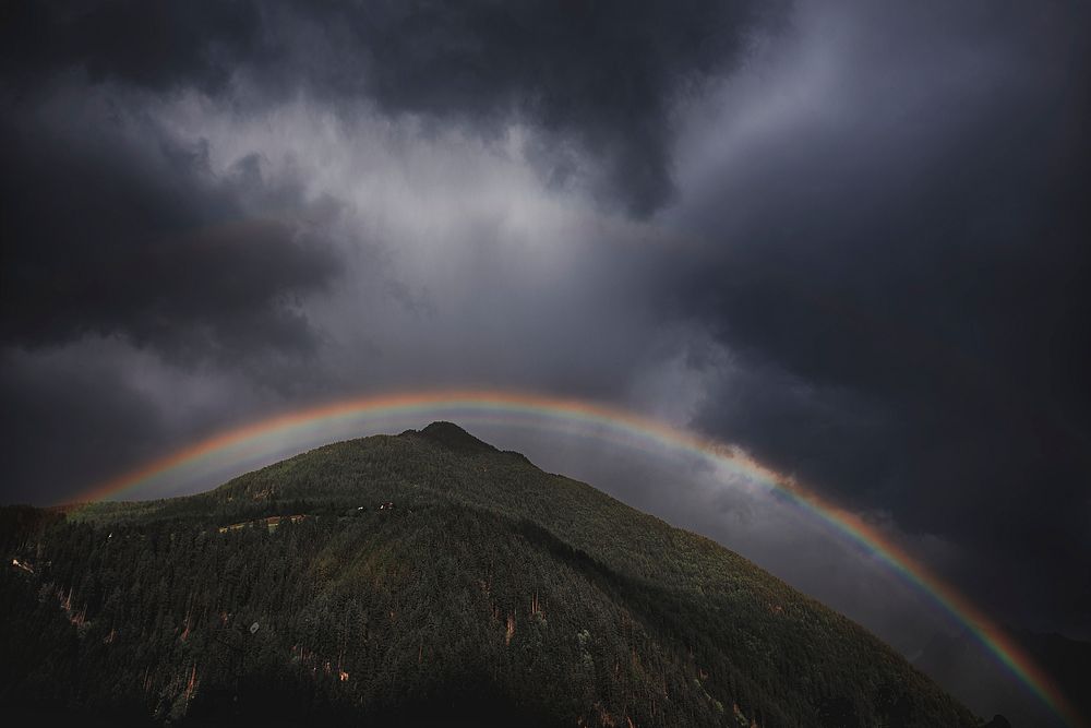 Rainbow with dark sky over the hill