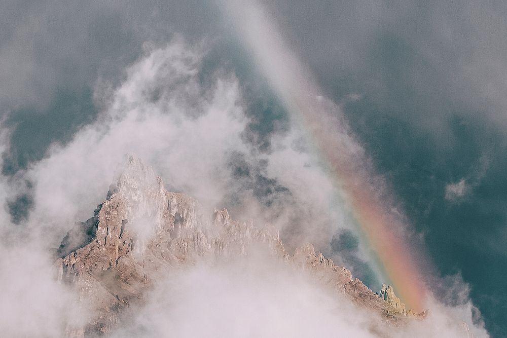 Mist and a rainbow over a rugged mountain in Alpe di Siusi, Dolomites, Italy