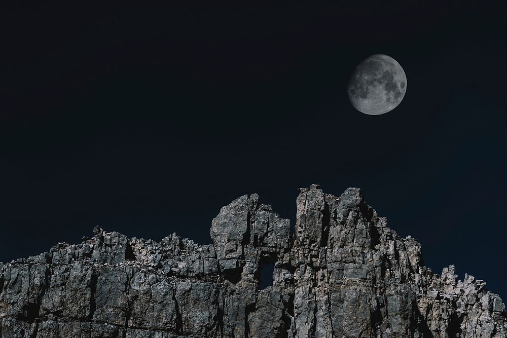 The moon over a rugged mountain cliff