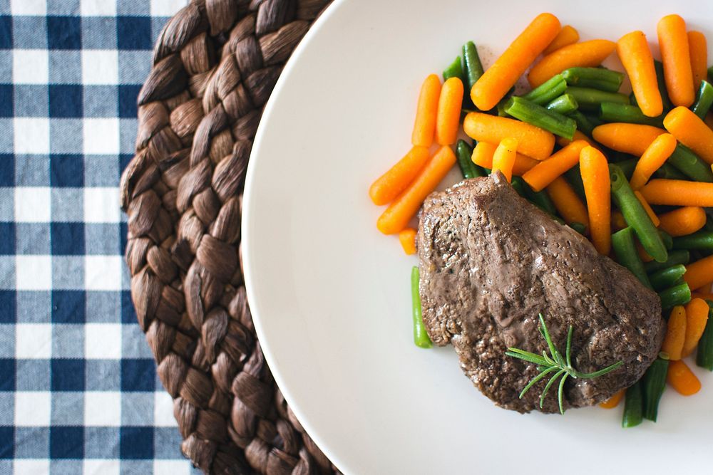 A beef steak with mini carrots and green beans
