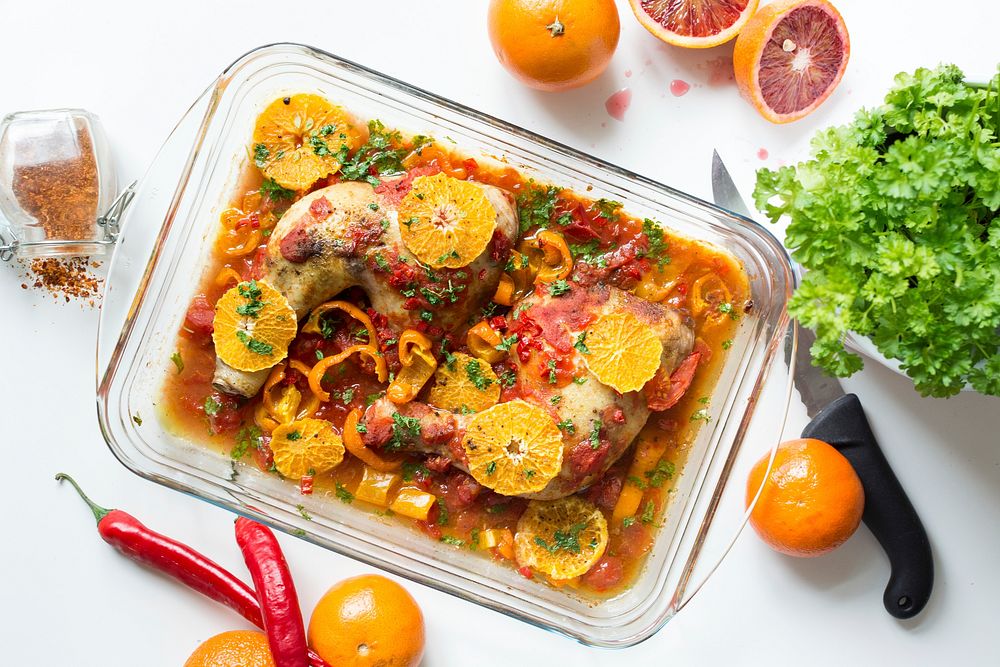 Chicken thighs with tomatoes, peppers, and oranges.