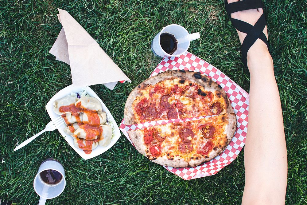 Woman eating salami pizza on the grass