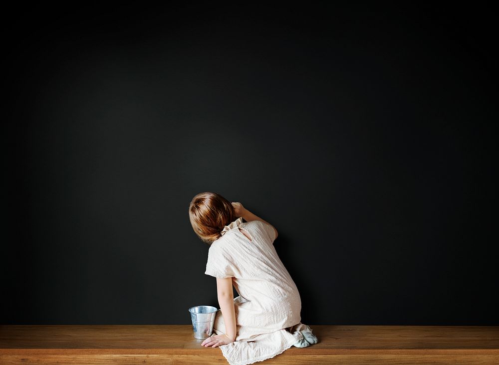 Little girl drawing on an empty black wall