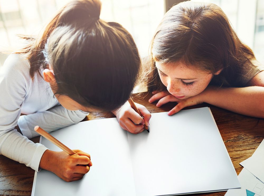 Girls writing and drawing on a white paper together copy space