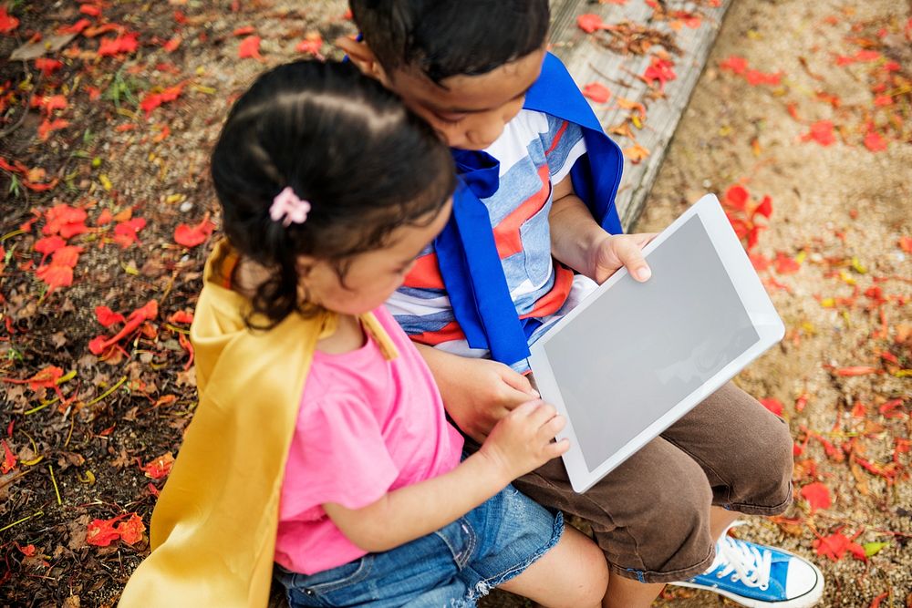 Superhero kids using an empty screen digital tablet