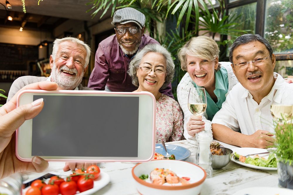 Senior friends in a restaurant taking pictures together