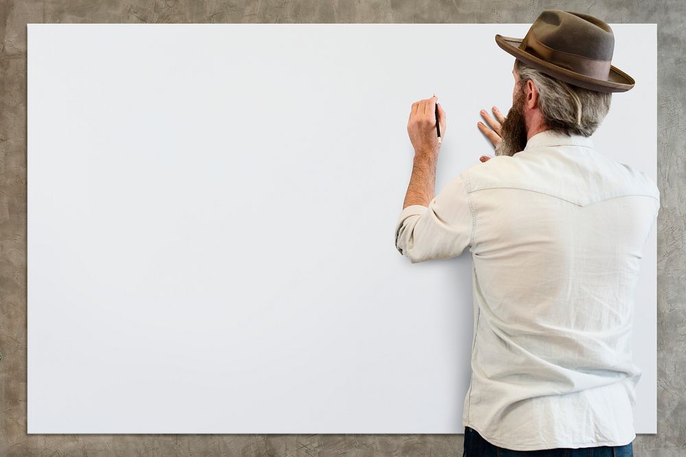 Guy with a hat writing on a blank board