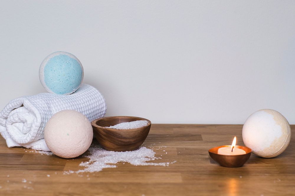 Three bath bombs with a towel, epsom salt, and lit candle, free public domain CC0 image.