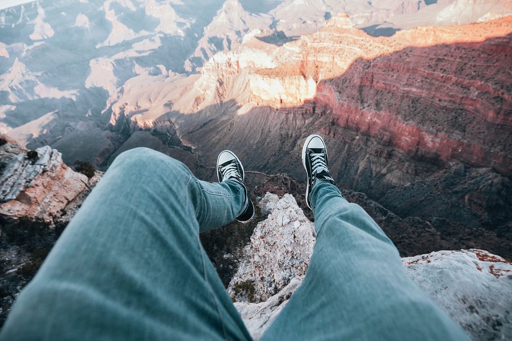 Person sitting on cliff, Grand Canyon, Arizona, free public domain travel CC0 photo.