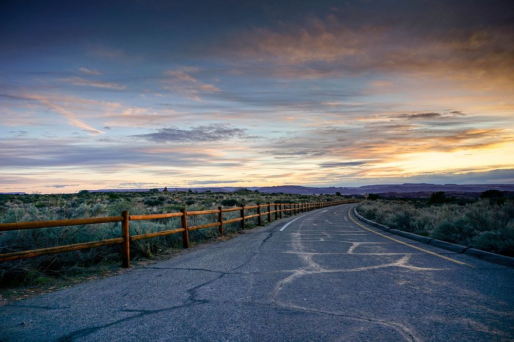 Empty country road with fence line at sunset.