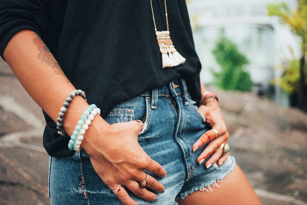 A close up of a young woman wearing denim shorts while holding the pockets as if ready to get on a horse and ride off into…