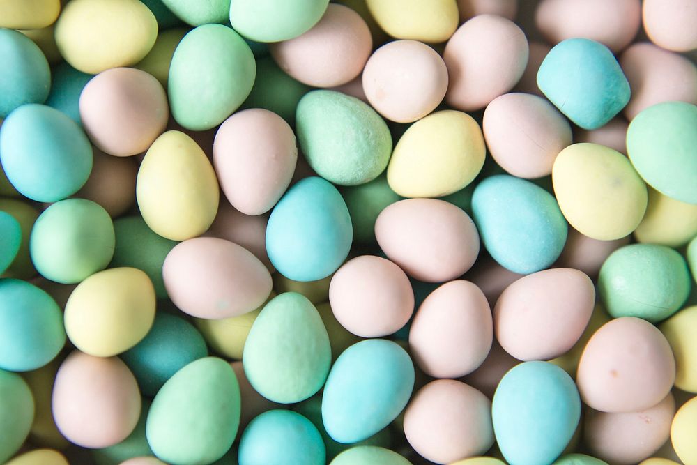 Hundreds of mini eggs fill the frame. The photo highlights the texture of the colorful chocolate Easter eggs.
